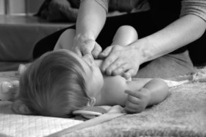 Maminka masíruje dítěti bříško proti nadýmání a bolesti.